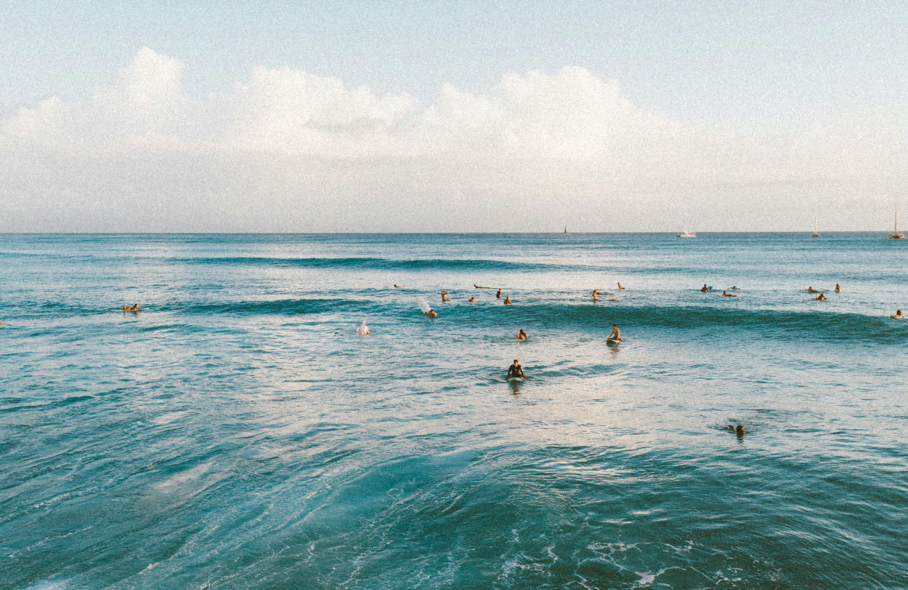 A peaceful image of surfers in the ocean, with the colors and feeling of freedom embodying the agency's core philosophy.